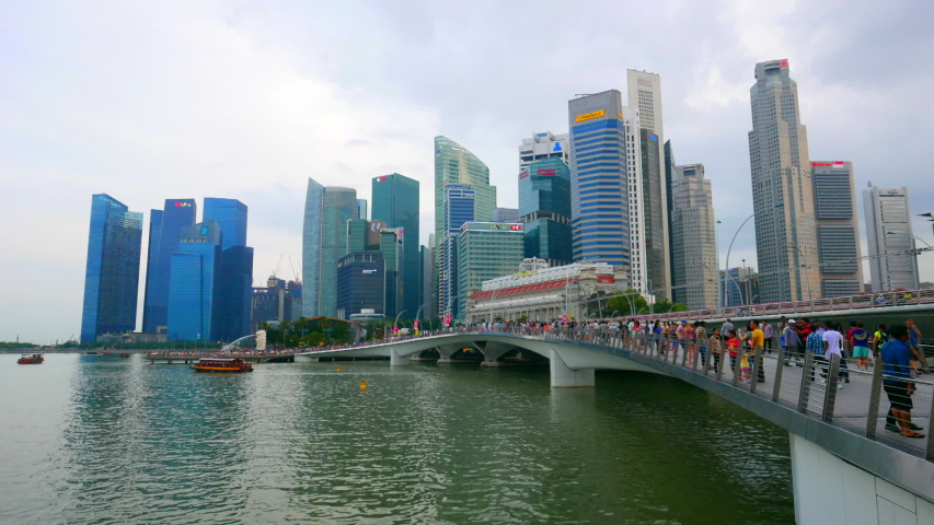 Singapore / Singapore - 03 18 2019: SIngapore - Circa Wide static time lapse of the Singapore city skyline with people walking over a bridge. | Shutterstock HD Video #1041691705