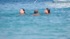 Blurred video - children play in blue summer sea. Happy childhood at sea. Active vacation and sports at sea. Children enjoy leisure and summer vacation at sea. Blurry people on video, for background.