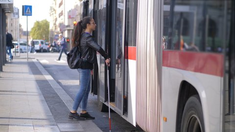 Young blind woman with her stick getting on bus. Transportation,autonomy,blindnes