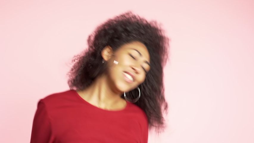 Beautiful african american woman with afro hair having fun smiling and dancing in studio against pink background. 4k | Shutterstock HD Video #1041707758