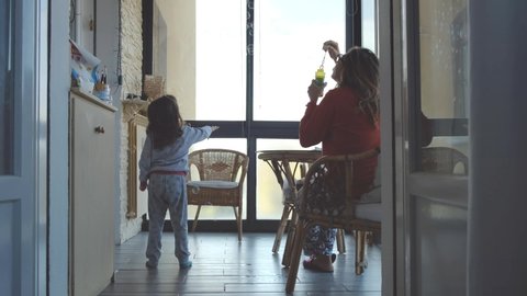 mom blowing soap bubbles in house porch at morning with pajamas mother children daughter together home baby girl .