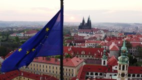 Aerial view town through waving flag on foreground. Lateral movement, drone shot, flying flag of EU in front of shining sun over scenic panorama Prague with red tiled roofs at sunrise - Powered by Shutterstock - Get 15% off with code: PIKWIZARD15