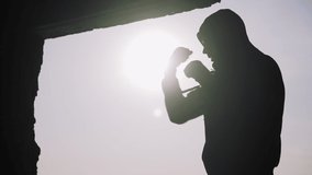Silhouette of a boxer on a sunset background. Coaches punches. Shadow-boxing. Outdoor workout. Motivational video. 