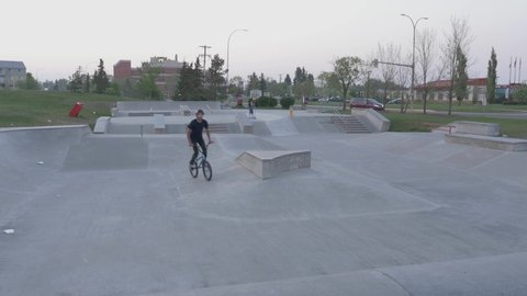 BMX rider does freestyle tricks at skate park.