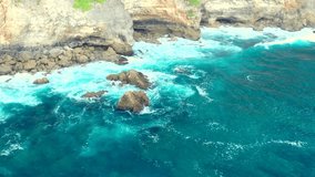 Indian Ocean, waves hit a cliff. Rocky coast. Video filming from the air flying over water. Uluwatu, Bali Island, Indonesia. 
