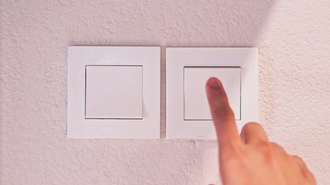 Close up hand to switching off the light at home. Finger push turn off light switch for saving energy after use. Save the world and conserve energy concept.