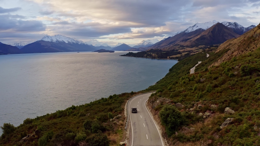 Aerial footage of the coastal road along the lake Wakapitu leading to Glenorchy from Queenstown in New Zealand south island at sunset with a dramatic sky Royalty-Free Stock Footage #1041759010