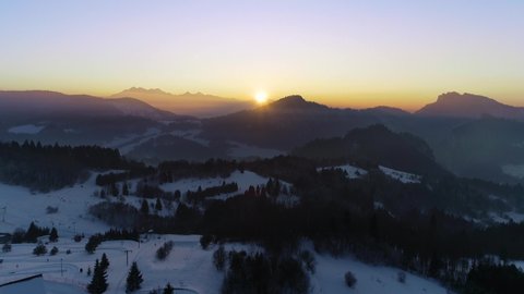 Aerial view of beautiful sunset in winter ski resort. Mountains covered with snow, sun is going down. Sunset time lapse in winter snowy season. Tatra mountains in the background. 