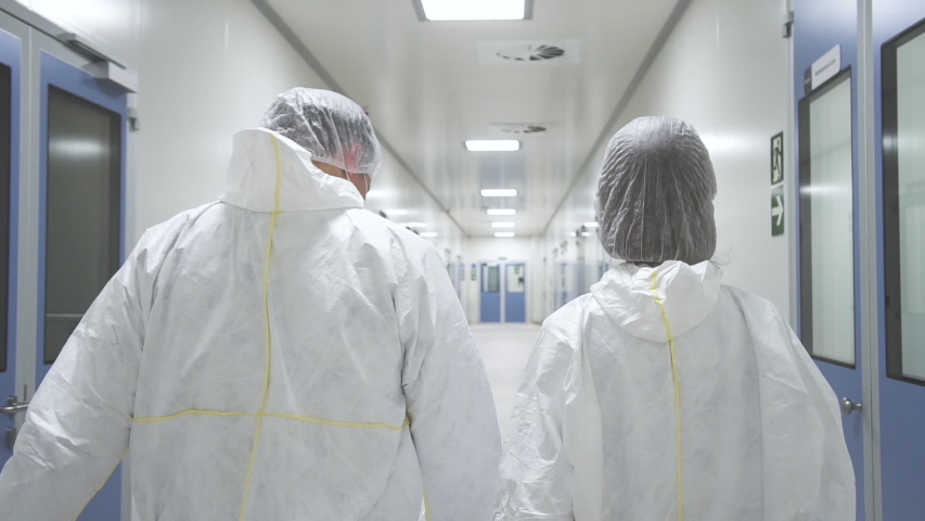 American man and woman worker walk and having talk in pharmaceutical plant. Two people employee discussing work ideas in interior of medical company. Back view of young staff wearing white protective | Shutterstock HD Video #1041766501