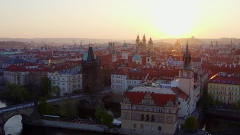 Aerial view downtown Prague and Charles bridge at sunrise. Picturesque cityscape from high, drone flying above water of Vltava river and Charles bridge lateral moving opposite old town embankment