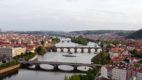 Aerial view Vltava river and bridges in Prague at daytime. Drone flying at low above pleasure boat moving In water, forward motion to manes bridge through Vltava river and buildings on embankment