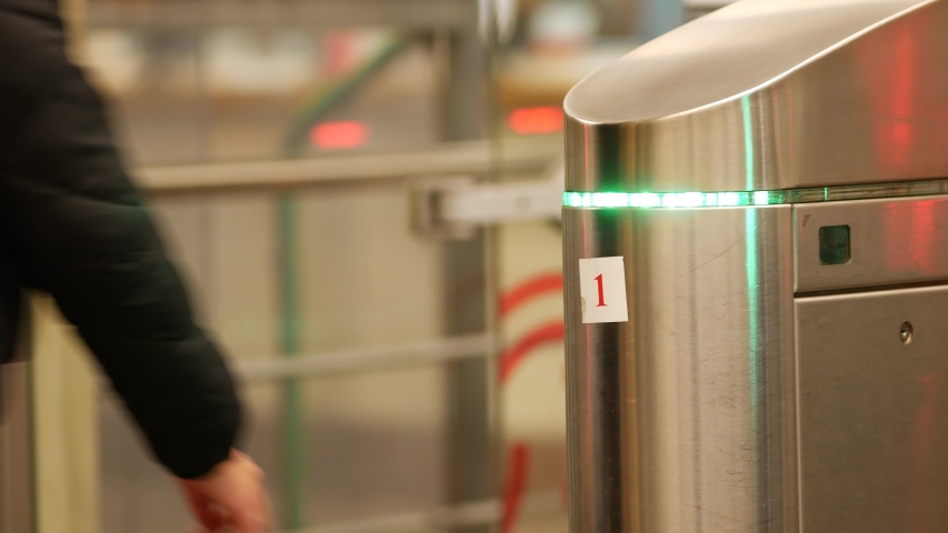 People go through subway turnstiles. Passengers exit the subway through the barrier. Automatic doors with motion sensors. Green gate light. Moscow, Russia. Public transport system