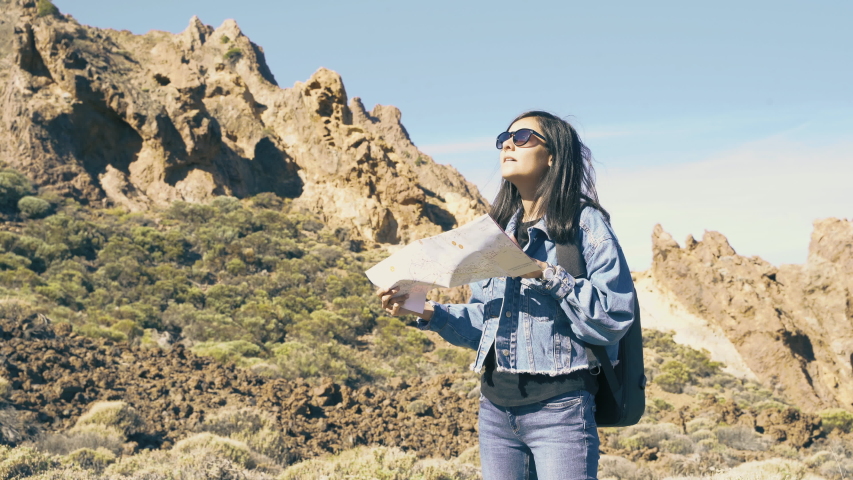 Young woman tourist with backpack and map enjoying mountain view.