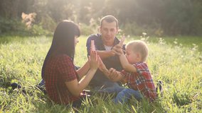 happy family teamwork lifestyle outdoors concept outdoors slow motion video. mom dad and a son in nature are sitting on the grass have fun. playing mom girl dad man and son boy happy family
