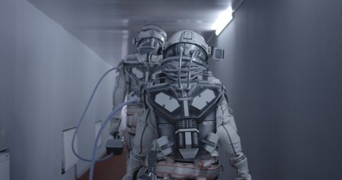 Medium shot of astronauts walking down a corridor to the launch pad