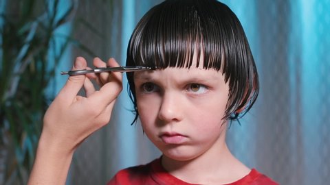Close-up of hair cutting on the boy's head. Wet hair is cut in a straight line. Baby haircut.