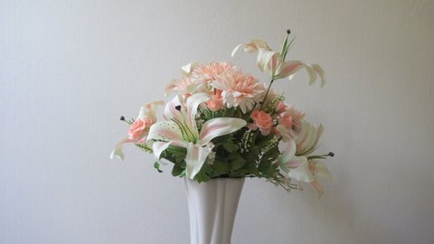 Lilies, roses, carnations flowers in pink vase on white background is rotating. Pastel flower collection presentation
