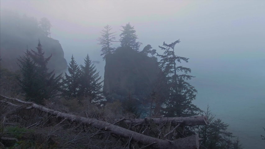 Aerial: flying over foggy calm ocean and rocky islands at sunset. Brookings, Oregon, USA 