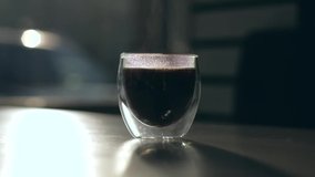 Cinematic video - silhouette of fresh coffee cup with steam rising in cafeteria. Slowmotion.