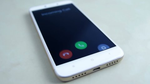 Incoming call on white mobile phone on tile