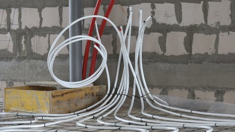 Underfloor heating system pipes hoses at construction site. Zoom out shot.