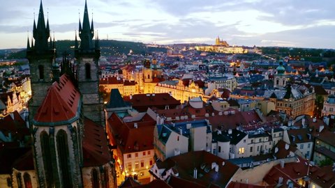 Aerial footage Church of Our Lady and easter market in Prague at twilight. Drone circling near cathedral over main square with illuminated street shop in old town. Picturesque cityscape at evening