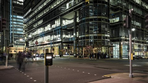 Busy city street at night time lapse with large office buildings