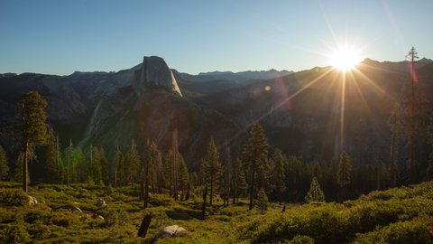 Yosemite National Park. Time lapse video of the sun rising up from behind the Half Dome Mountain. The valley and mountains emerge from the darkness, lit by the first rays of the morning sun.