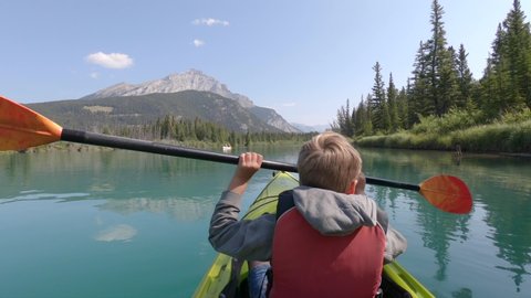 Kayak canoe in Banff Alberta Canada. Floating on Bow river in Canadian national park nature. Summer time adventure activity with child