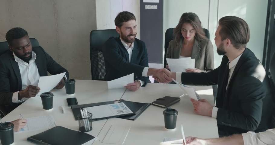 Group of Successful Business People Sitting in the Meeting Room Having a Deal. Working at Ofice Building. Discussing about New Progressive Project. Leaders Shaking Hands while Making Contract