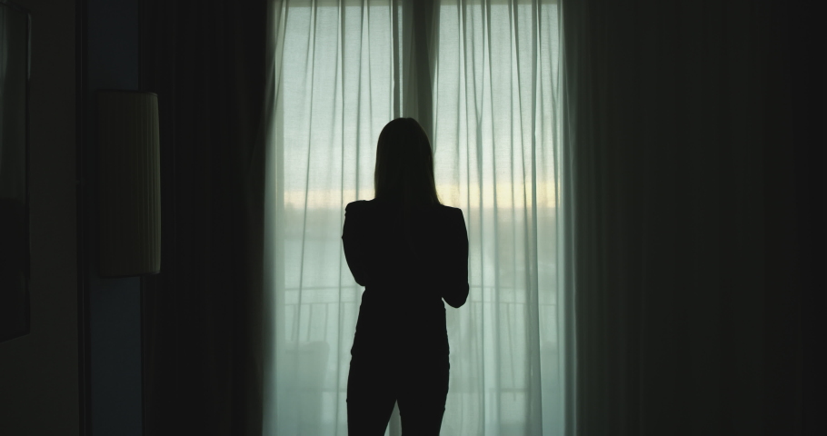 An young woman is opening window curtains in a hotel room to enjoy the panoramic view in morning during a vacation. Royalty-Free Stock Footage #1041852667