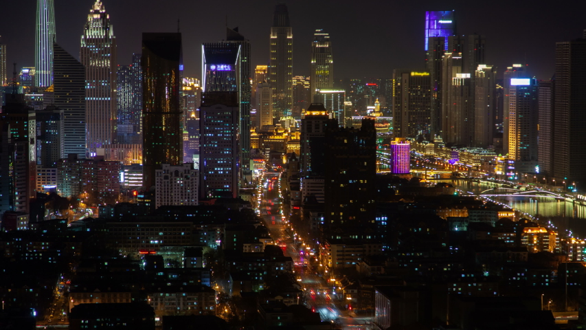 Timelapse flashing advertisements on Tianjin city highrise buildings in Chinese Heping District with wide highway and high skyscrapers at dark night