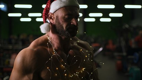 Bodybuilder Santa clause drinking water after workout. Sport muscular fitness man cross fitness and bodybuilding Christmas and New year concept gym abs muscle exercises in gym torso fitness 