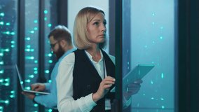 Attractive woman IT specialist with tablet checking network and data servers working on rack. Blonde female technician coworking with male engineer at data center. - Powered by Shutterstock - Get 15% off with code: PIKWIZARD15