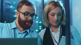 Couple of IT server engineers coworking running diagnostics operations in rack server room examining software webhosting at high secure data center. - Powered by Shutterstock - Get 15% off with code: PIKWIZARD15