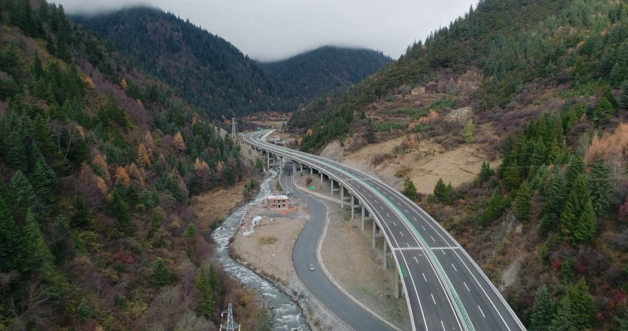 Winding elevated highway in the beautiful valley of an aerial view.Beautiful tree covered valley with winding roads and flowing streams.The valley dotted with convenient traffic and a winding river.