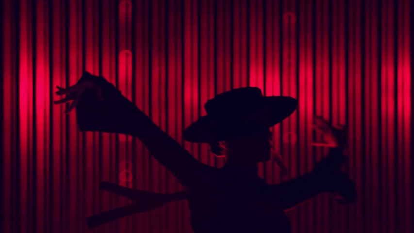 Beautiful hat dressed girl dancing latin dance . Professional female dancer dancing flamenco , rumba or salsa on red background with lines . Spanish dance movements . Shot ARRI ALEXA Cinema Camera .