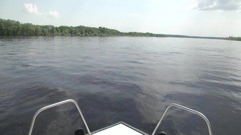 The motor boat is moving at high speed. A boat ride on the river. Forest river under a blue cloudy sky. view from motorboat. Clouds are reflected in the river.
