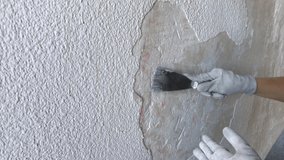 Video 4K. Young hipster girl makes repairs in the flat. Clean old plaster on the walls before paint into new white color. Works with putty knife .