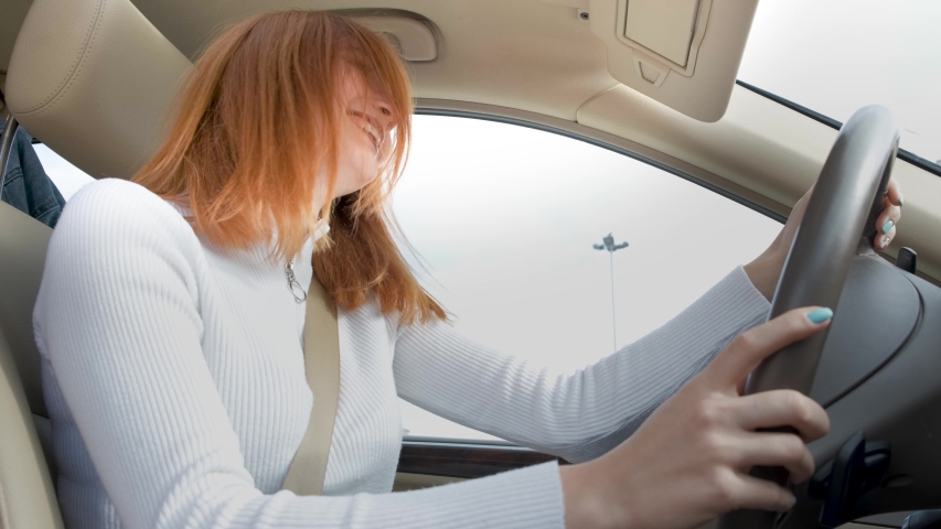 Young woman driver having fun behind the wheel listening to music in a car.