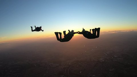 Skydivers make a formation skydive at the sunset slow motion