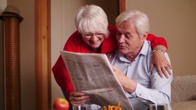 Happy senior couple reading newspaper at home - Powered by Shutterstock - Get 15% off with code: PIKWIZARD15