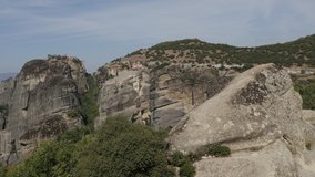 Tourists with cars and buses on Greek Meteora rock formations 4K panning video