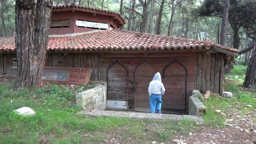 Akyaka, Mugla, Turkey - 10th of November 2019: 4K Kid cautiously knocks on the door of a shabby hut
