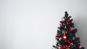 Decorated Christmas tree on right side of frame with garland on white background