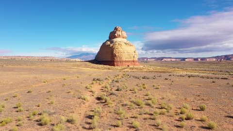 Church Rock monument of beige rocks stands alone in dried red sandstone desert on western United States in Utah national park. Amazing beautiful landscape of desert nature. Aerial fly forward and up