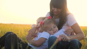 happy family mom and children laughing outdoors in the park slow motion video. mom tickles daughter and son lying on the grass funny funny video smiles laugh. little boy and girl with mom laugh relax