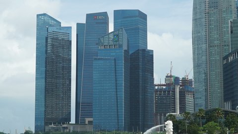 Singapore / Singapore - 03 21 2019: Singapore - Circa city skyline of business district downtown in daytime. Timelapse of city scape with a ferries on the water front.