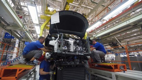 BELARUS, BORISOV - AUGUST 7, 2019: Automobile plant, modern production of cars, workers assemble the chassis and engine of the car, car body, build process in automated production line.
