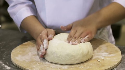 cook, Baker or pastry chef rolls dough for pizza or pie